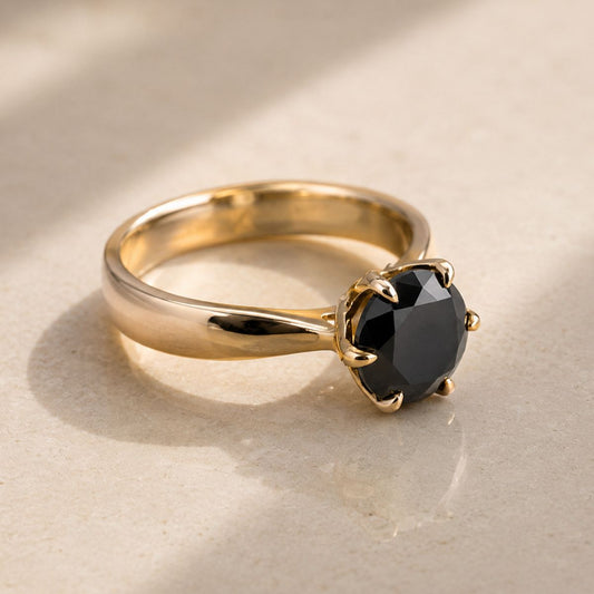 Gold ring with a black gemstone on a beige background
