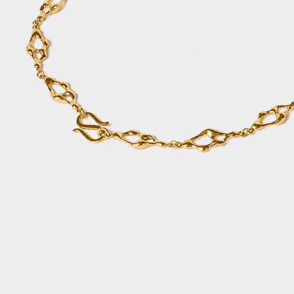 Sculptural gold necklace detali with organic openwork links arranged in a flowing circular composition