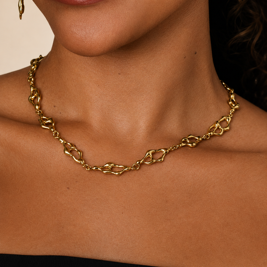 Gold chain necklace on a person's neck against a neutral background