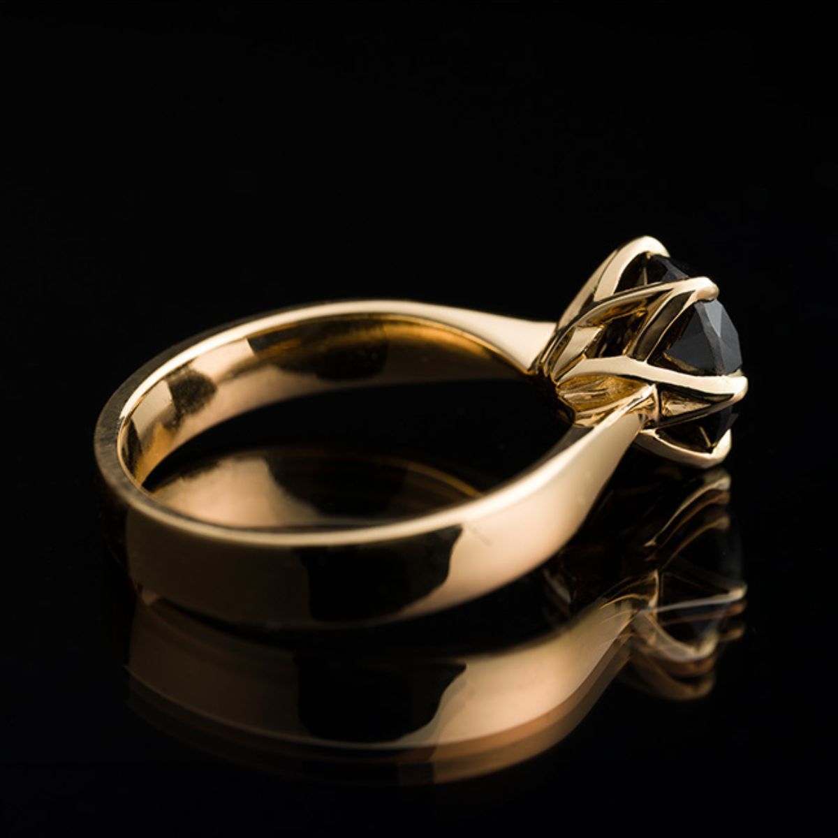 Gold ring with a black diamond on a dark background side photo