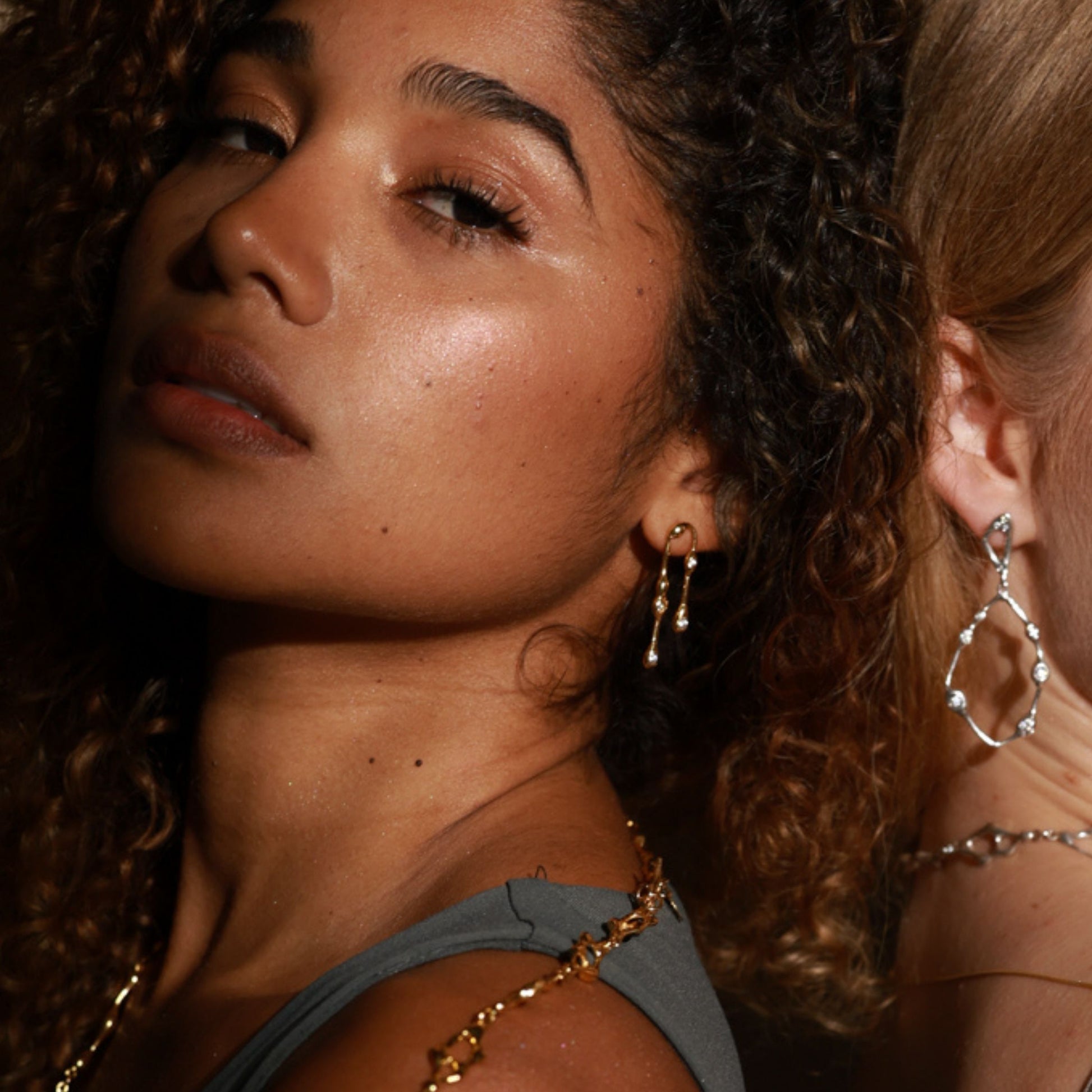 Close-up of two women wearing earrings with a warm, soft focus background.