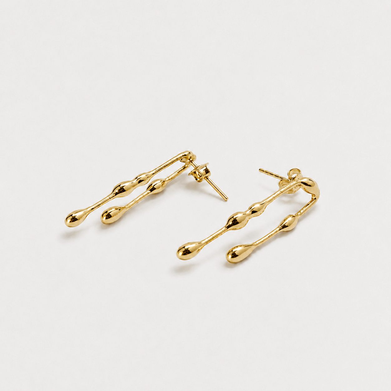Gold earrings on a light gray background