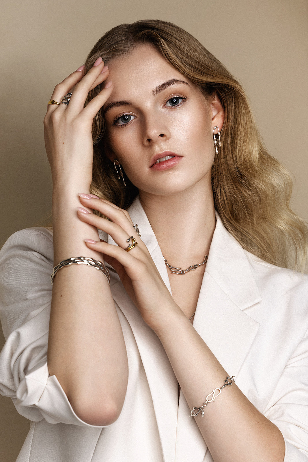 Woman wearing multiple pieces of JYOCO drop collection jewelry against a neutral background