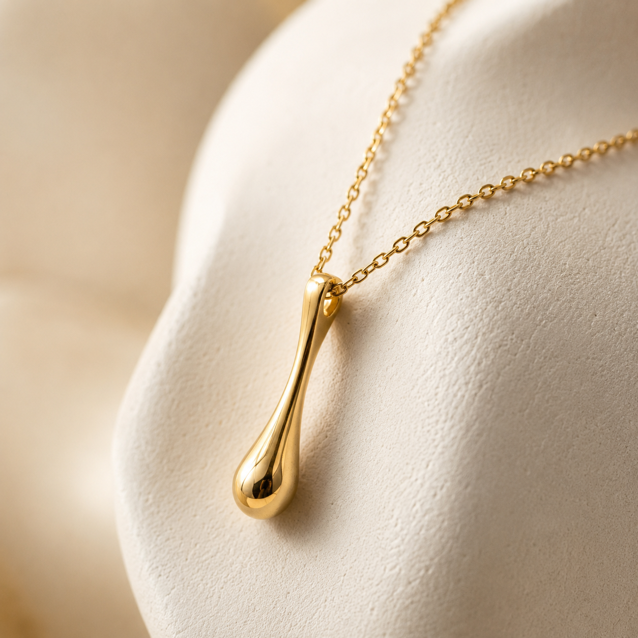 Gold necklace with a pendant on a white surface