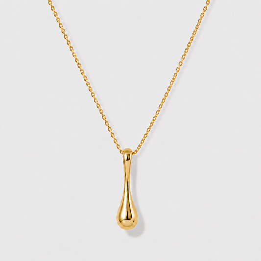 Minimal sculptural gold drop pendant necklace on delicate chain against soft neutral background
