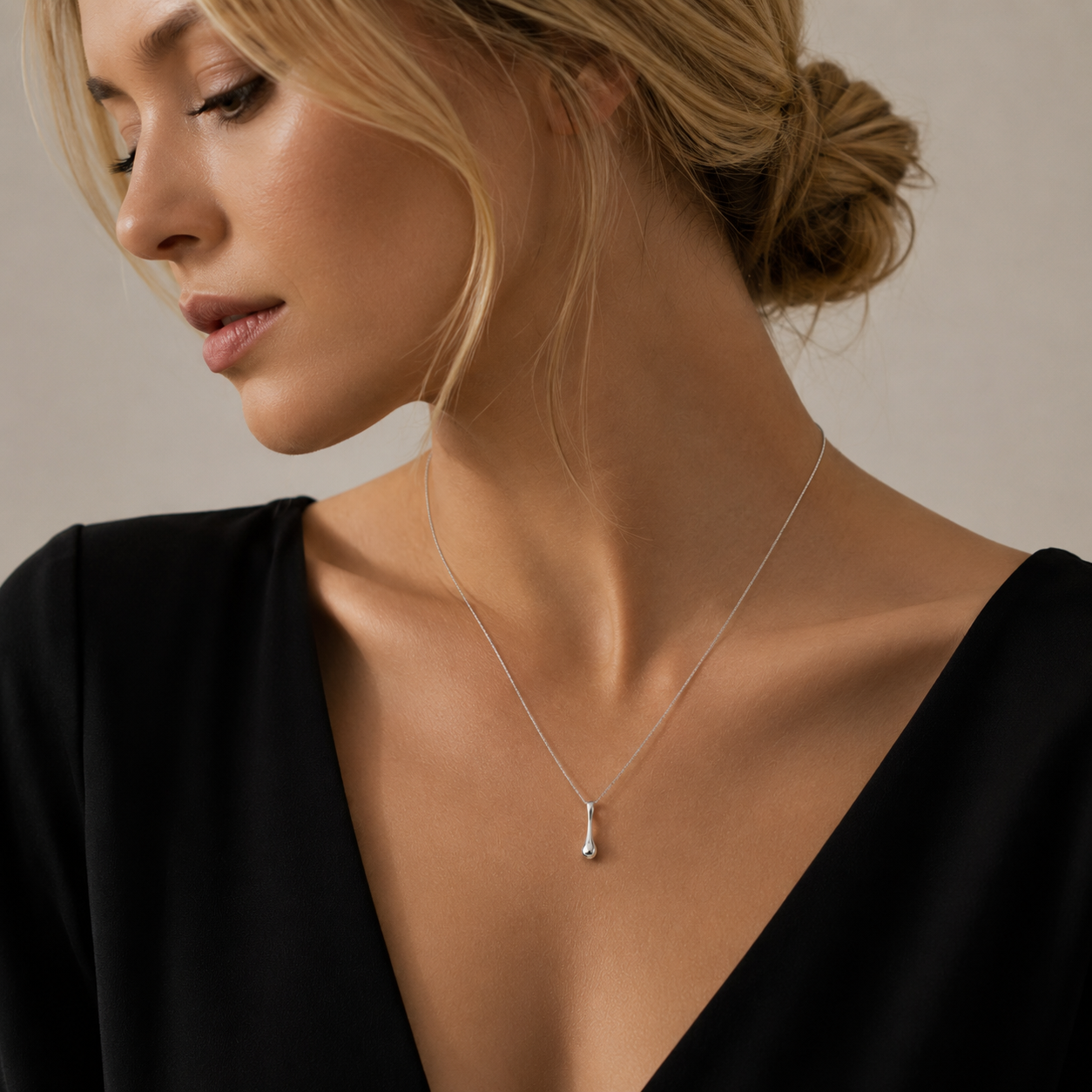 Woman wearing a delicate necklace against a neutral background