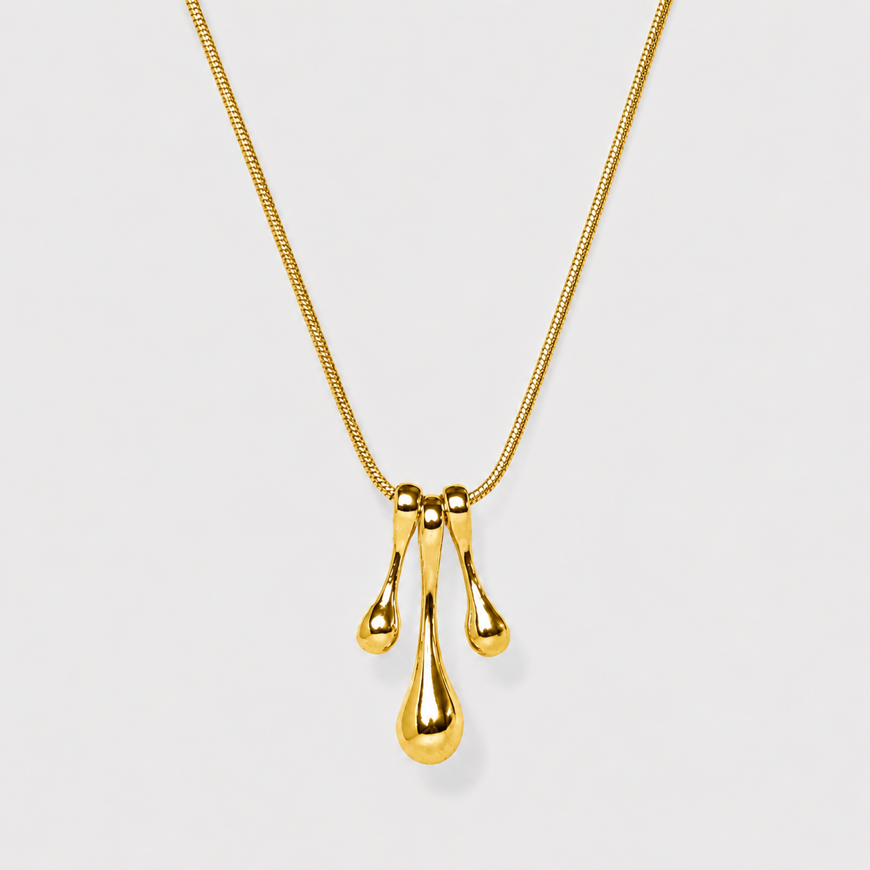 Gold necklace with a three-drop pendant on a light gray background