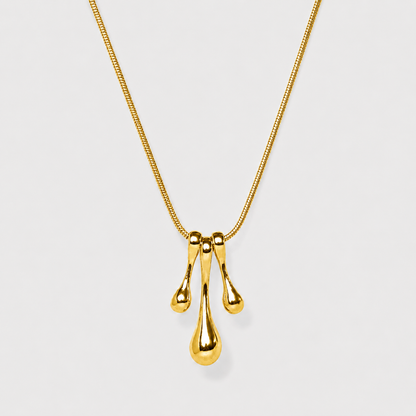 Gold necklace with a three-drop pendant on a light gray background