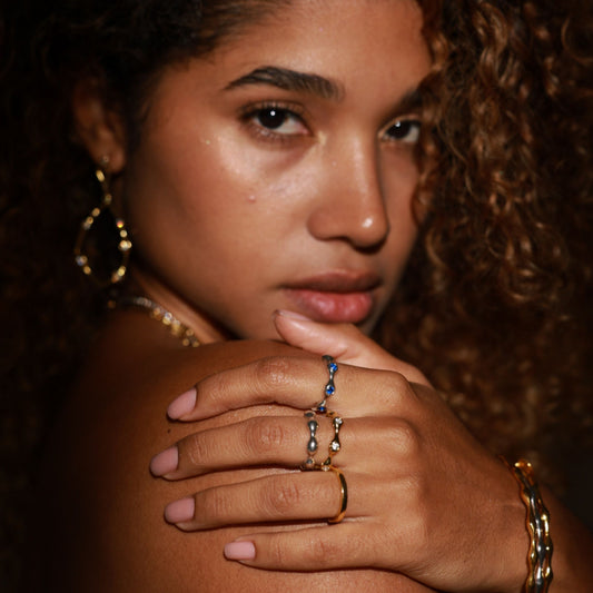 Close-up of a person with jewelry on their hand against a dark background