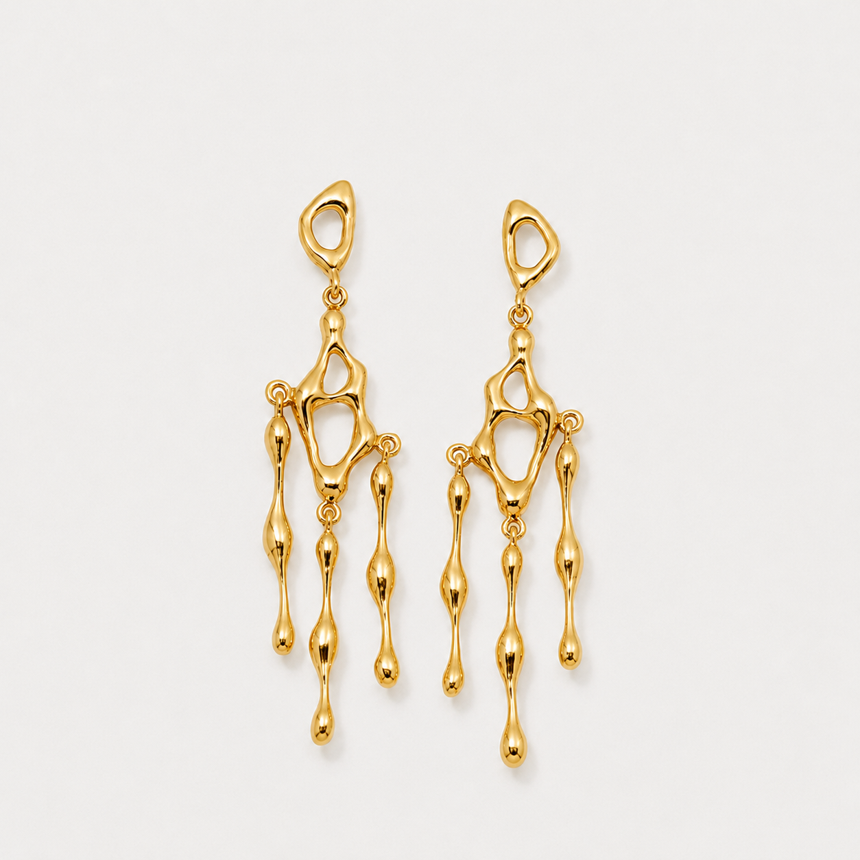Gold earrings on a light gray background
