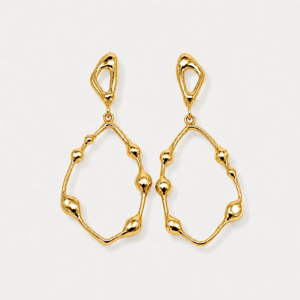 Gold earrings on a light gray background