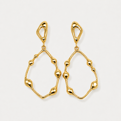 Gold earrings on a light gray background
