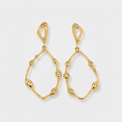 Gold earrings with diamond-like stones on a light gray background