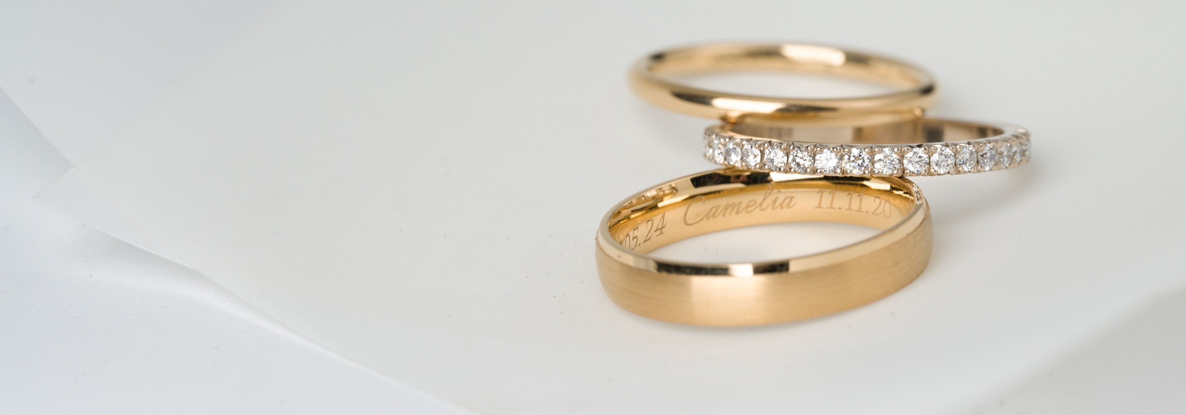 Three gold rings with diamond accents on a light gray background by JYOCO
