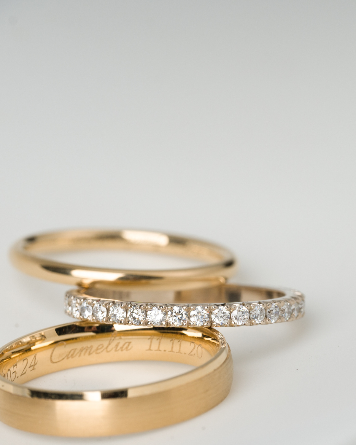 Two gold rings with diamond accents on a light gray background made by JYOCO jewellery to order