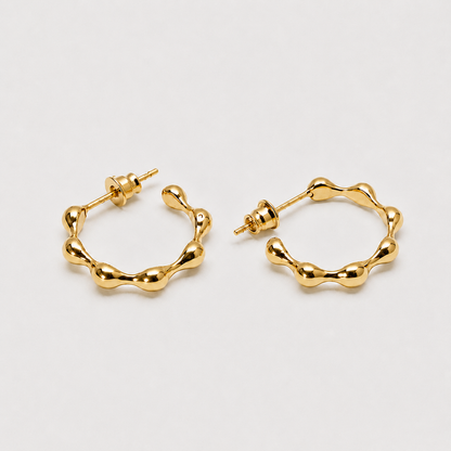 Sculptural gold hoop earrings with organic flowing silhouette and polished finish