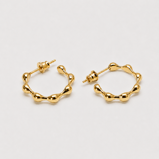 Sculptural gold hoop earrings with organic flowing silhouette and polished finish
