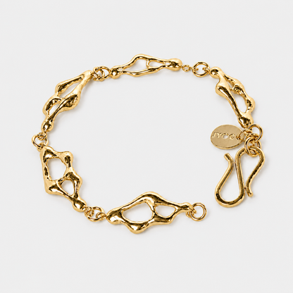 Gold chain bracelet on a light gray background