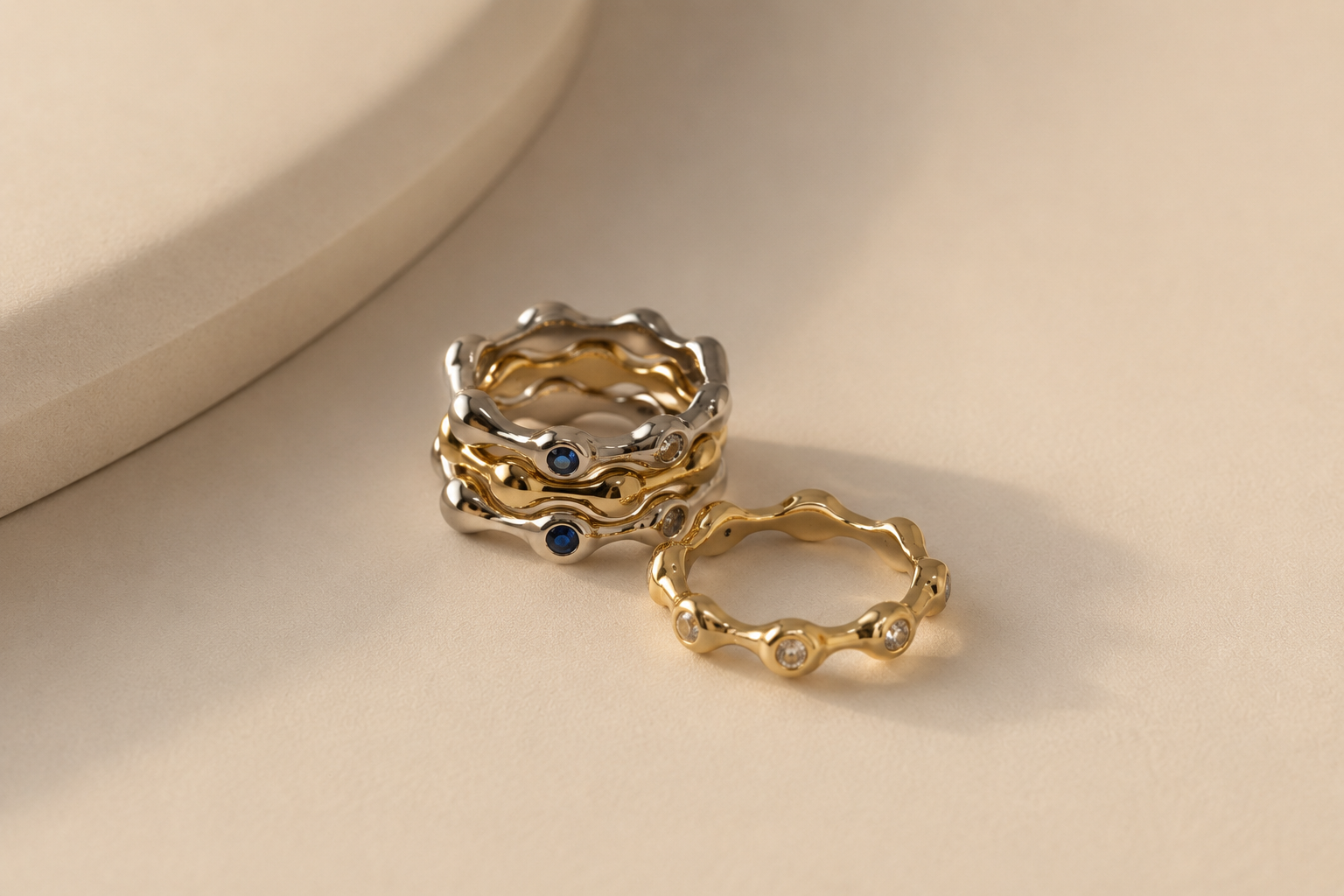 Two gold rings with embedded stones on a beige surface