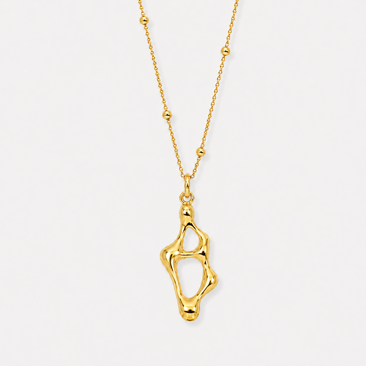 Abstract sculptural gold pendant necklace with organic open form on delicate beaded chain