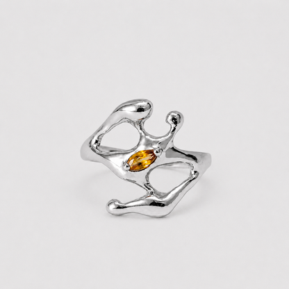 Silver ring with a central amber stone on a light gray background