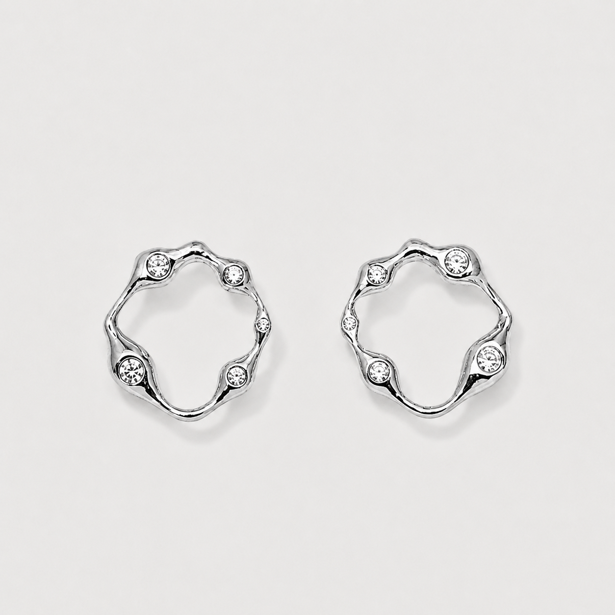 Pair of silver hoop earrings with small crystals on a light gray background