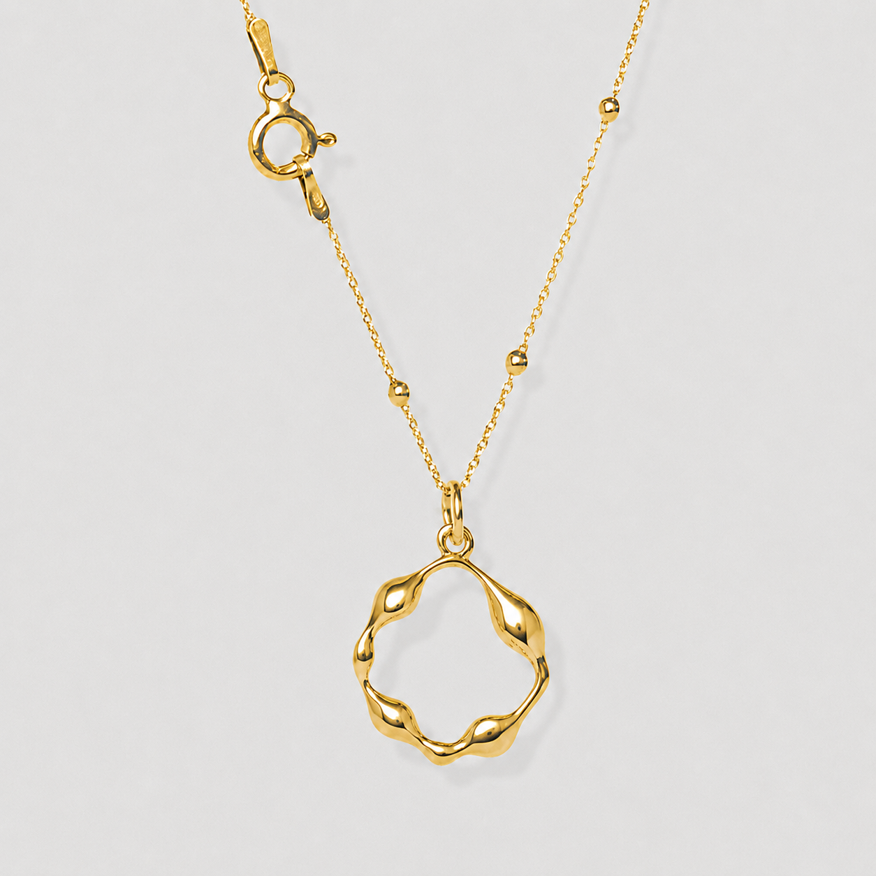 Gold necklace with a unique pendant on a light gray background