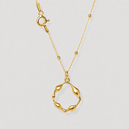 Gold necklace with a unique pendant on a light gray background