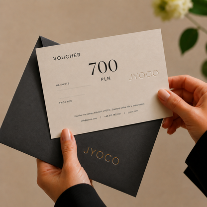 Person holding a JYOCO voucher with a black envelope against a neutral background